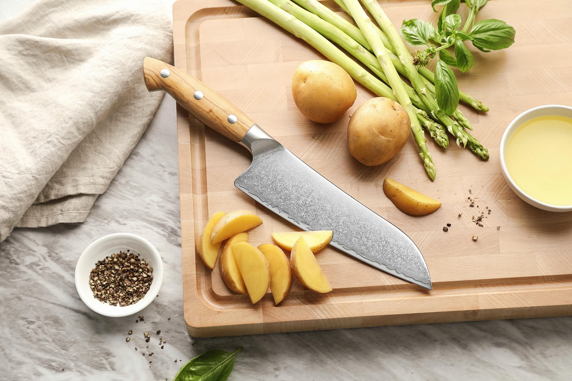 Santoku nůž XinZuo Pin X02O položený na prkénku